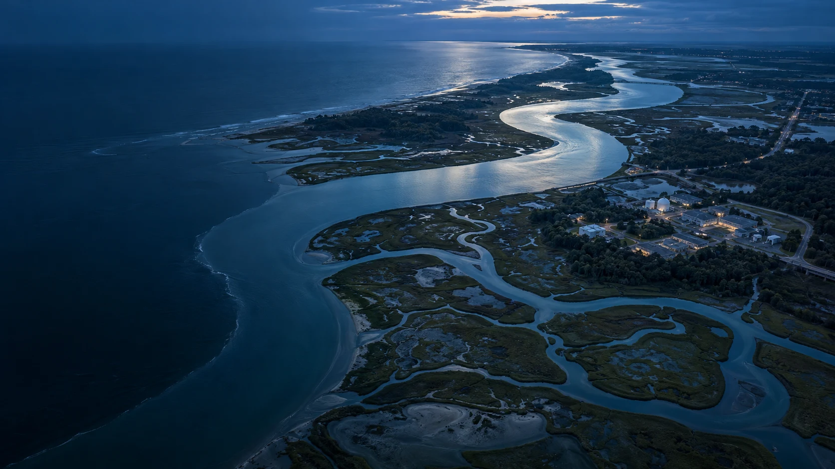 Concept aerial view of a coastal estuary, roads and buildings at blue hour